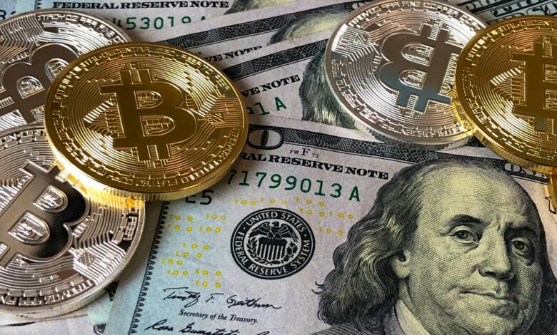 A close-up photo depicting Bitcoin coins on top of US dollar bills, symbolizing finance and cryptocurrency.