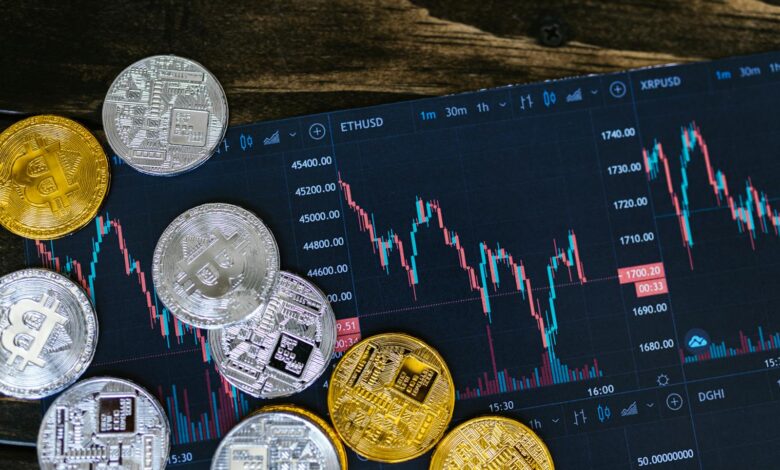 Close-up of gold and silver cryptocurrency coins on a digital trading chart.