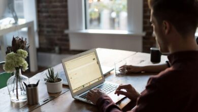 man operating laptop on top of table