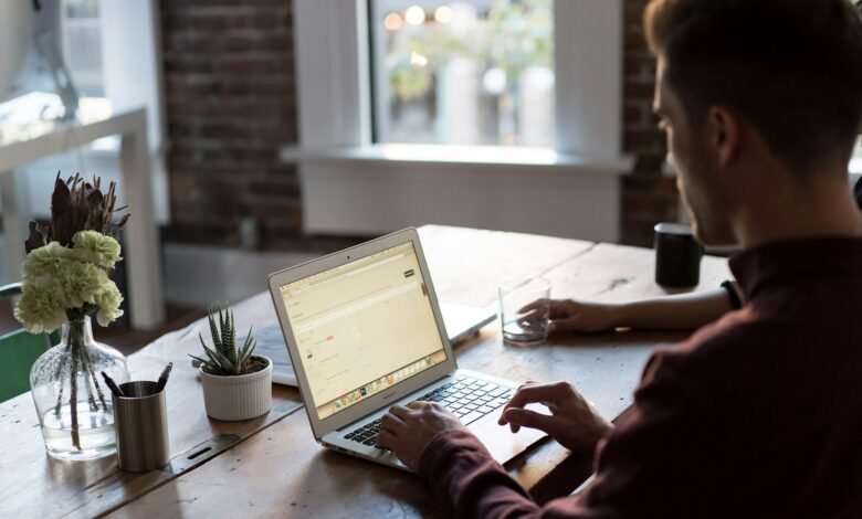 man operating laptop on top of table